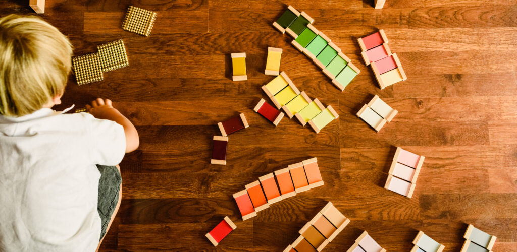 A young boy playing with different tactile learning materials on the floor. 