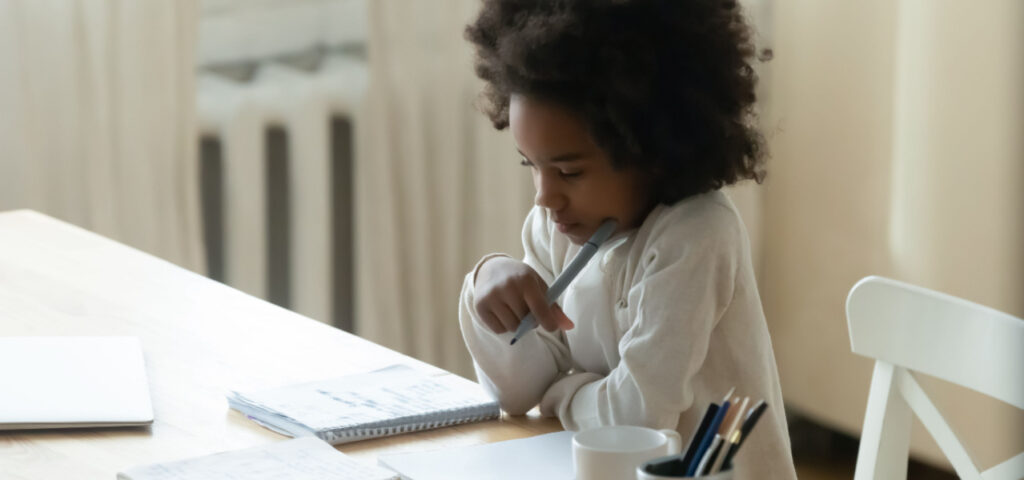 Young girl in deep thought while working on a homeschool assignment. 