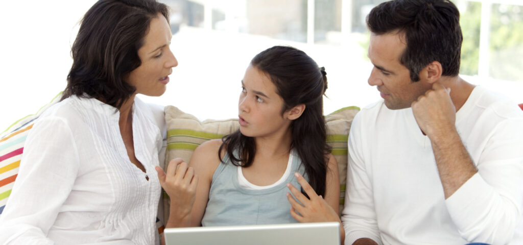 A young girl sitting in between her parents having a discussion about something. 