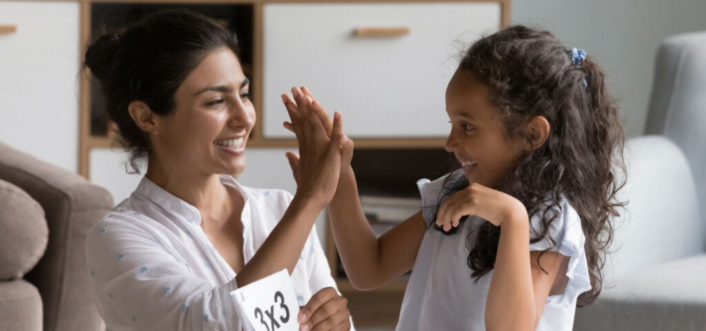 Mom working on times tables with daughter and giving her a high five. 