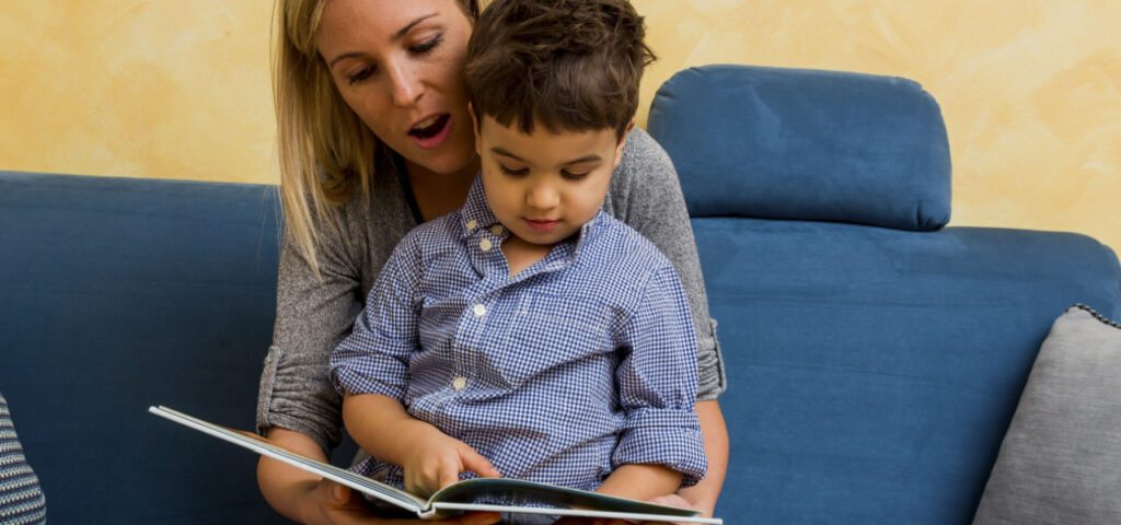 Mother reading to her son sitting on her lap. 