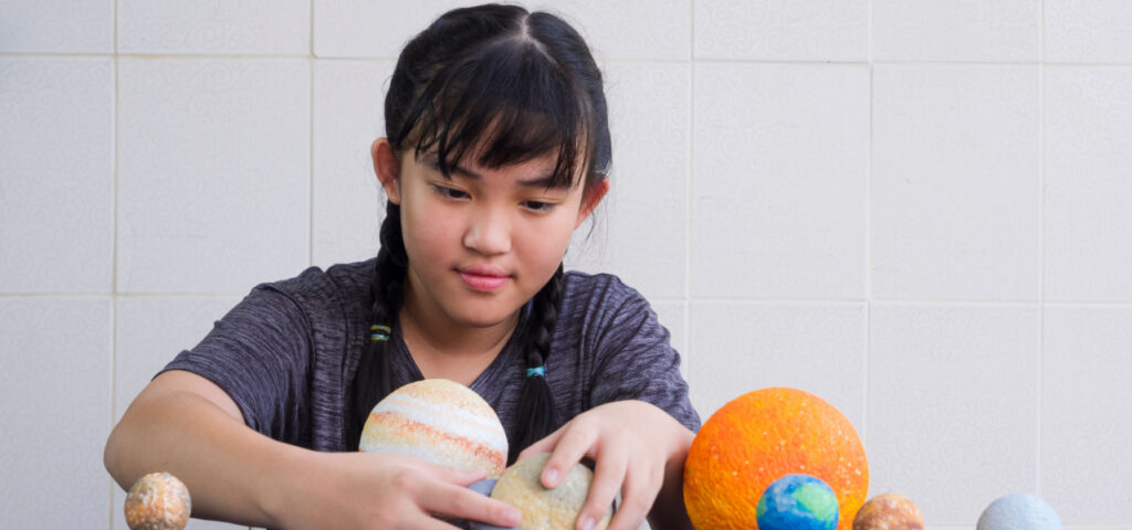 a girl putting together a solar system unit study project