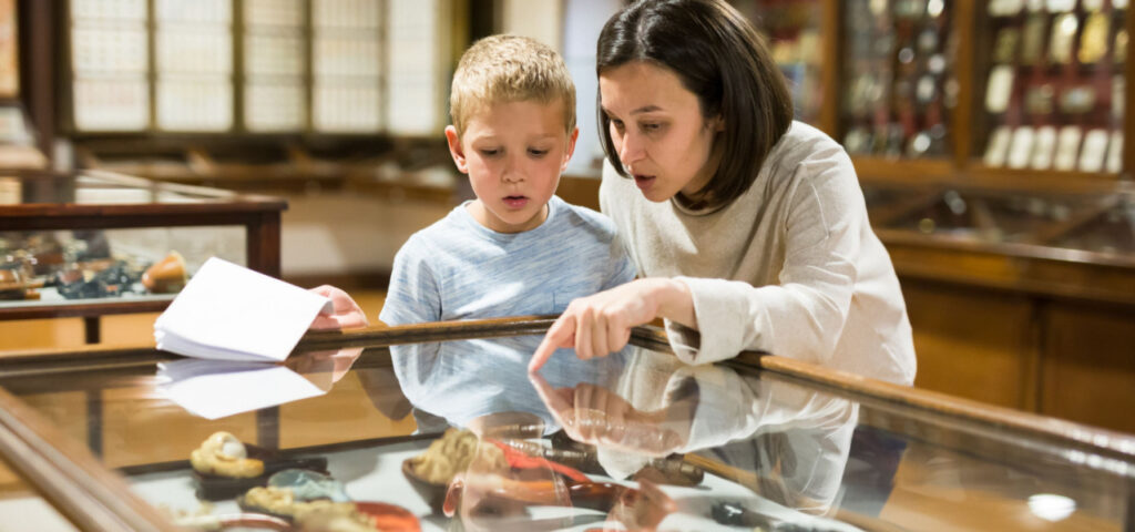 Child and mother looking at objects in a museum together. 