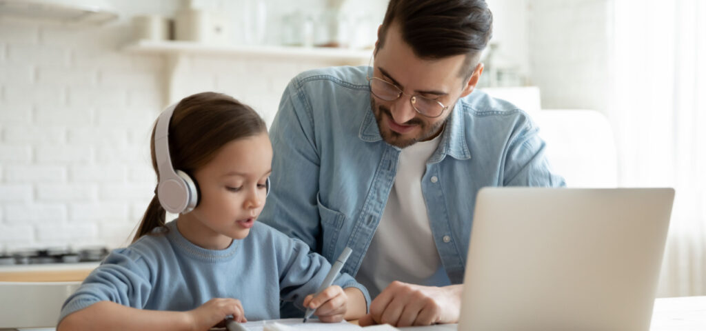 Daughter and father working on a school assignment in front of a laptop. 