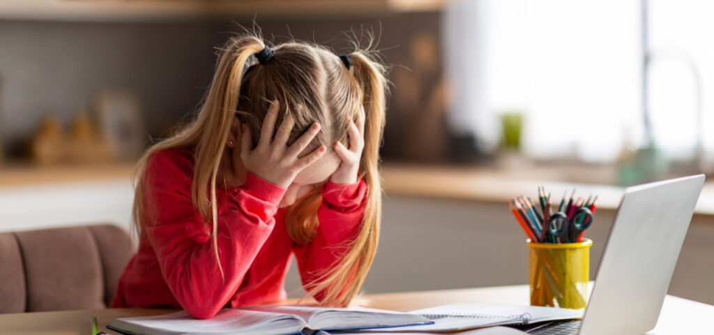 A young girl struggling with reading and holding her head in frustration. 