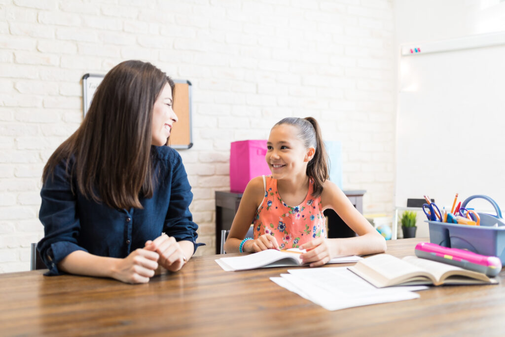 Mother and daughter sitting at the table working on homeschool. 